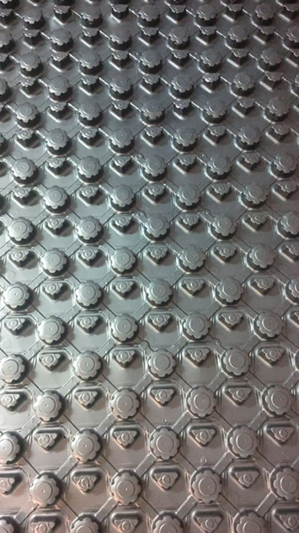 Oberfläche einer Systemplatte von Daikin mit hexagonalem Muster und runden Erhöhungen, gefertigt aus Metall, in grauer Farbgebung.